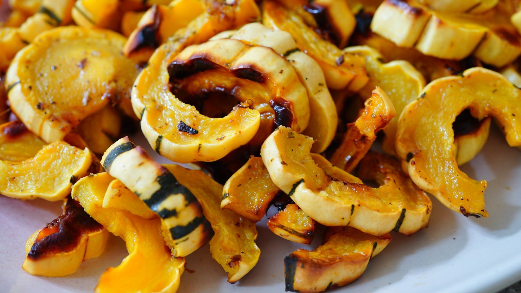 Roasted slices of delicata squash on a plate.