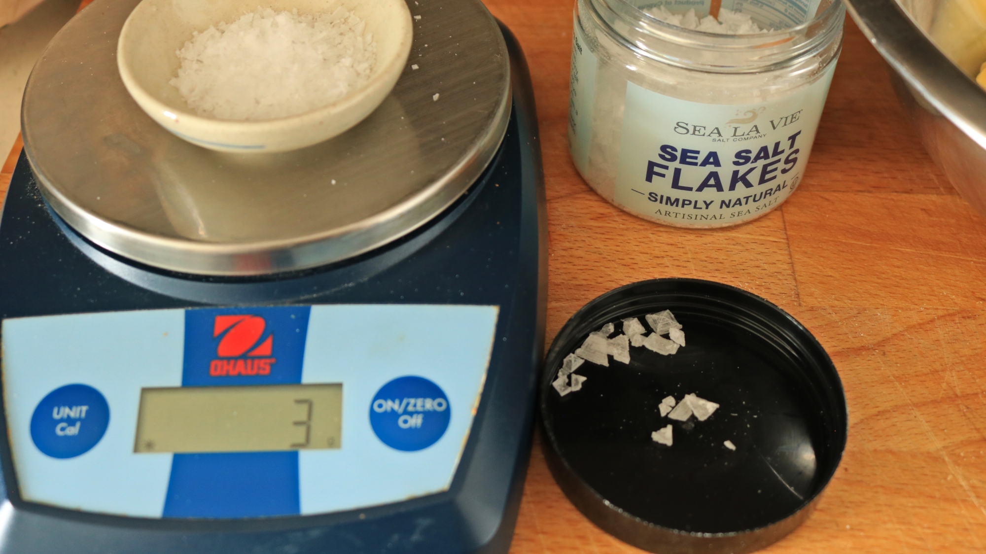 A kitchen scale with a small bowl of salt being weighed on top.